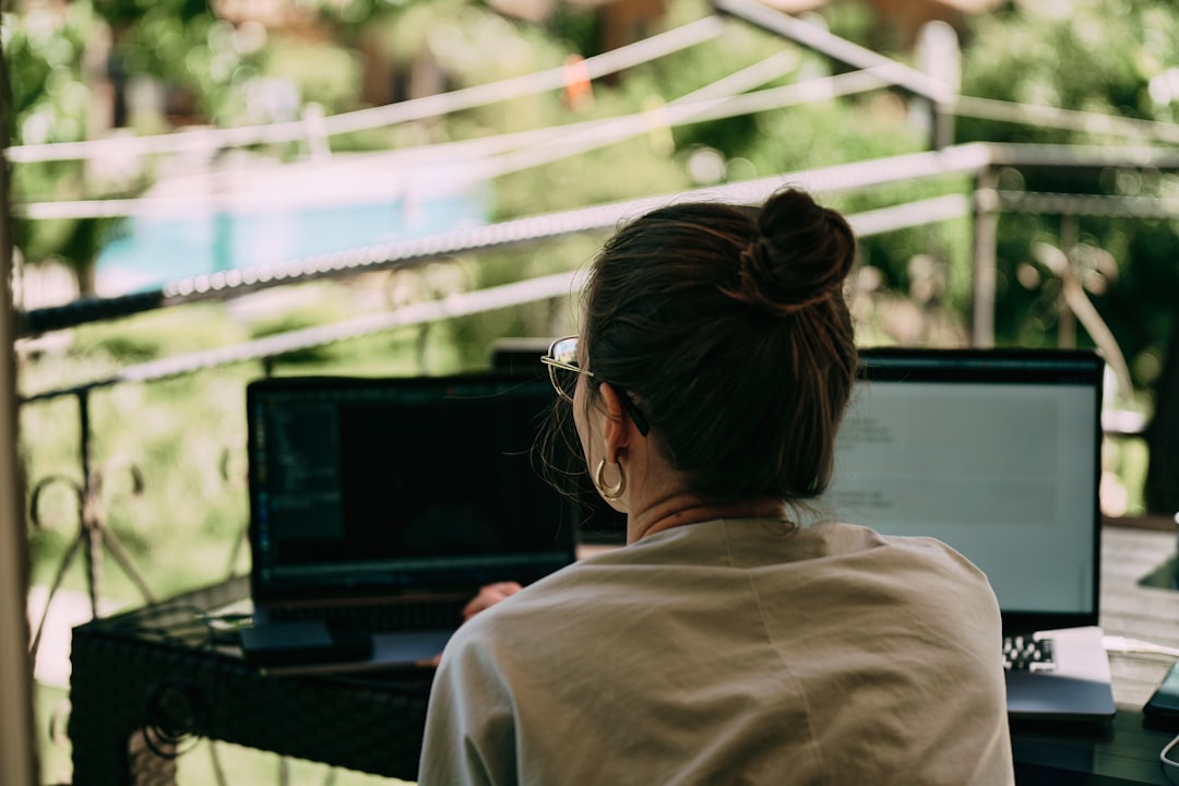 A girl working on the table on the terrace. Many laptops and other staff. Back view
